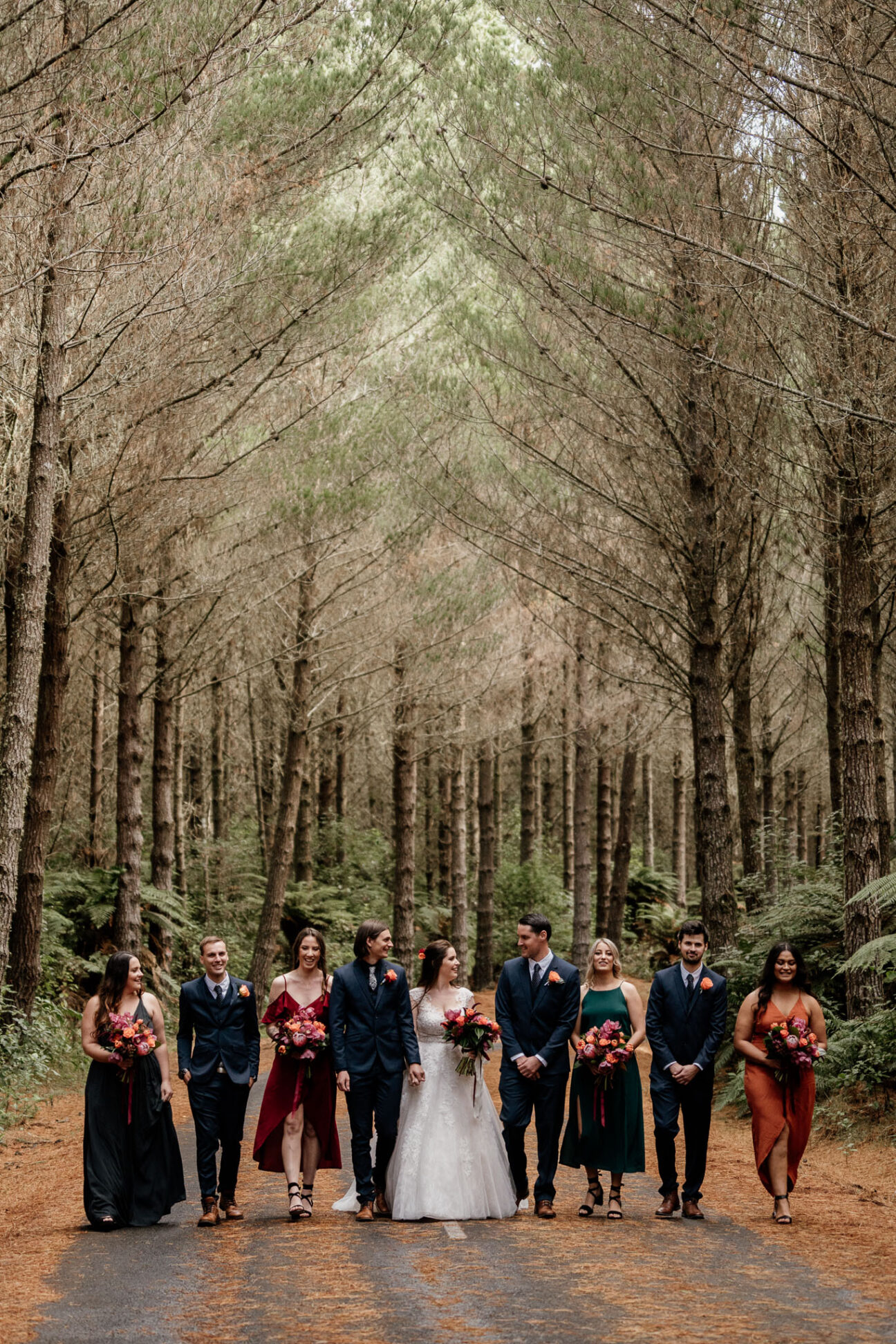 Autumn wedding in New Zealand Rotorua forest with winter colours bridal party walking on road