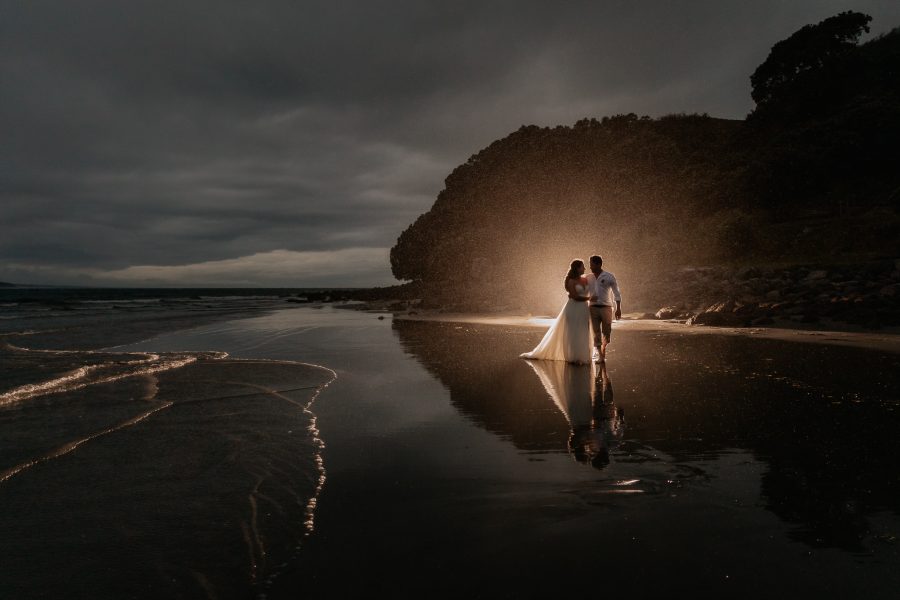 Back lit photo at night time during the rain and stormy seas wedding photo