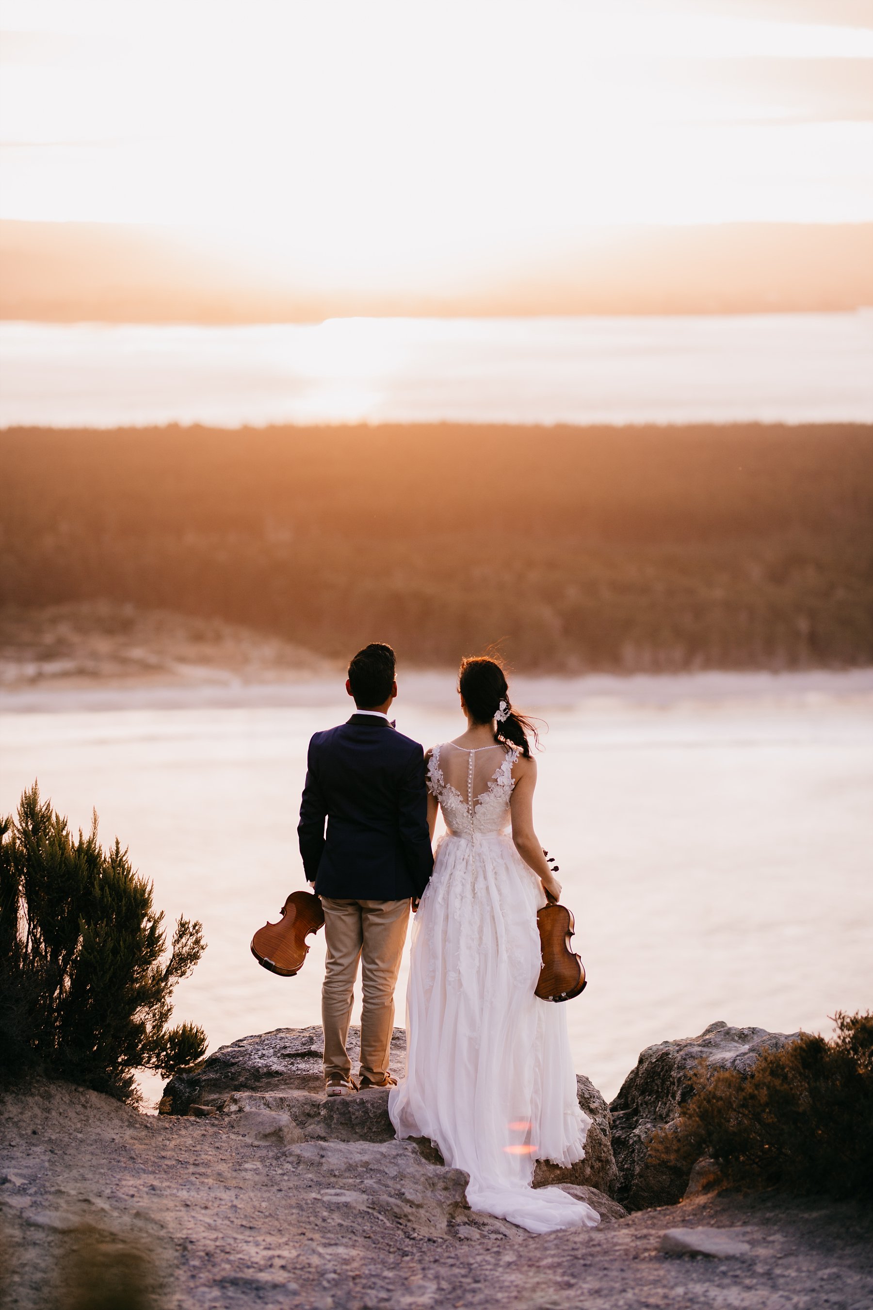 elopement wedding on top of Mount Maunganui with Matakana Island views at sunset holding violins