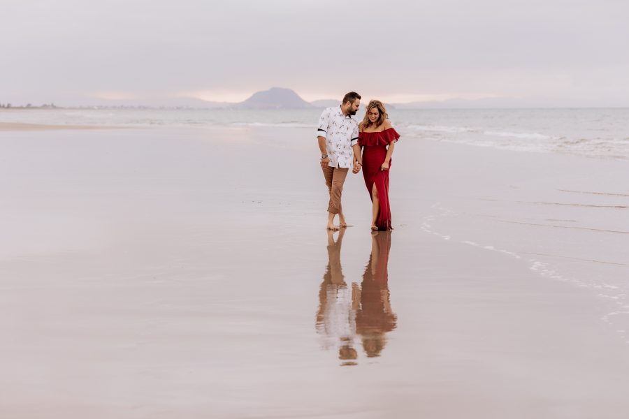 Couple walking on beach, red dress