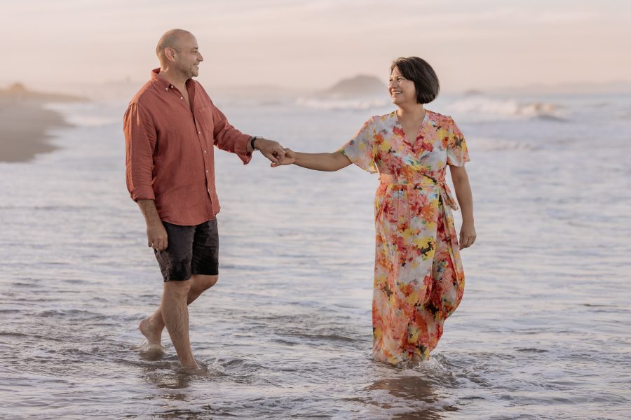 Couple walking in the water at golden hour for engagement shoot with Papamoa photographer