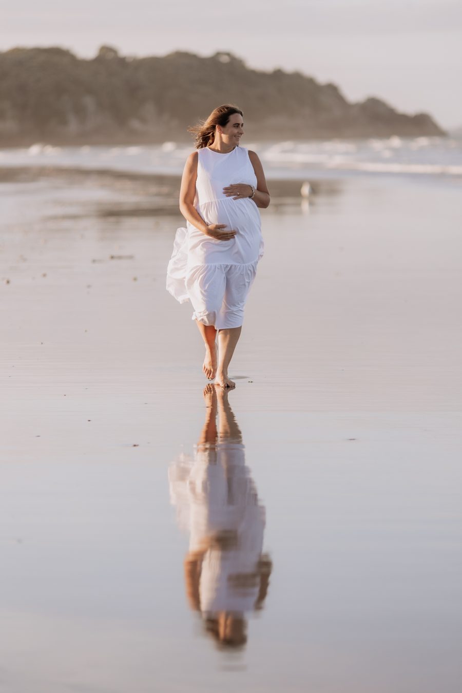 Maternity photos walking with reflections in sand at mount Maunganui