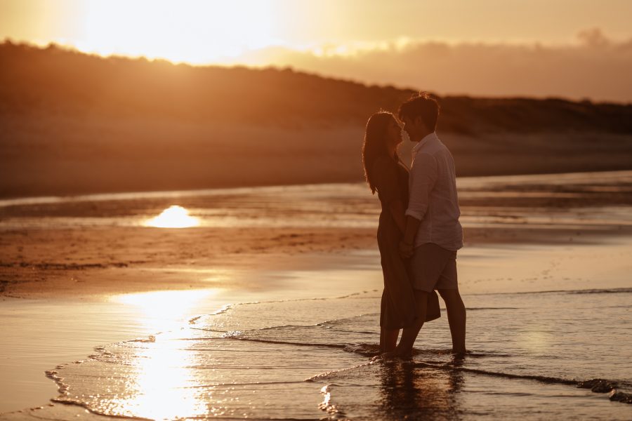 Dark golden photo of couple in water on beach photos