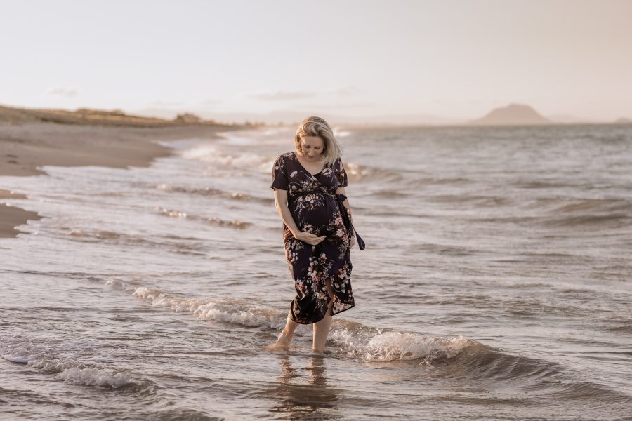 Maternity shoot of Mum walking in golden hour in the waters at Papamoa beach