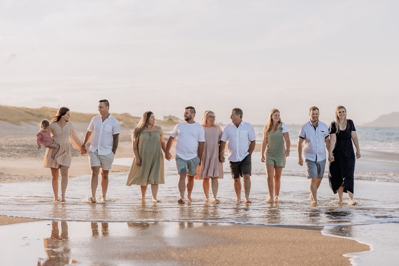 Family photo on Papamoa beach everybody walking wearing pastel clothing