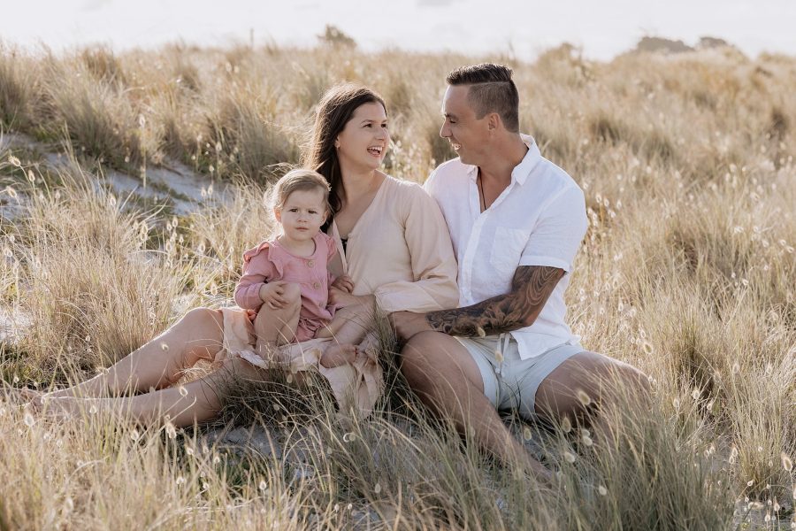 Young family with child sitting in sand dunes in photo portrait session with Pure Images Photography