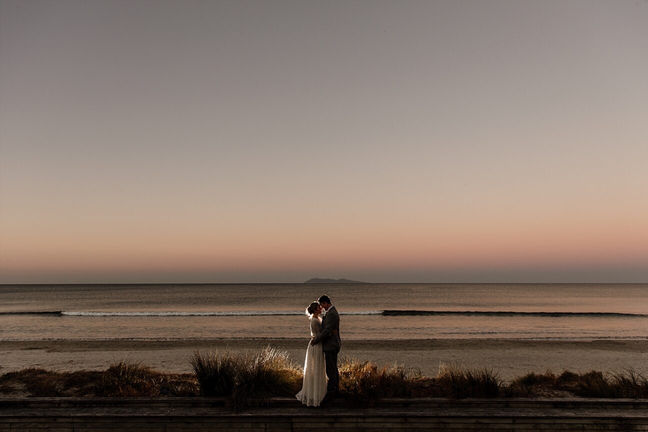 Waihi Beach sunset with wedding couple in front of beach