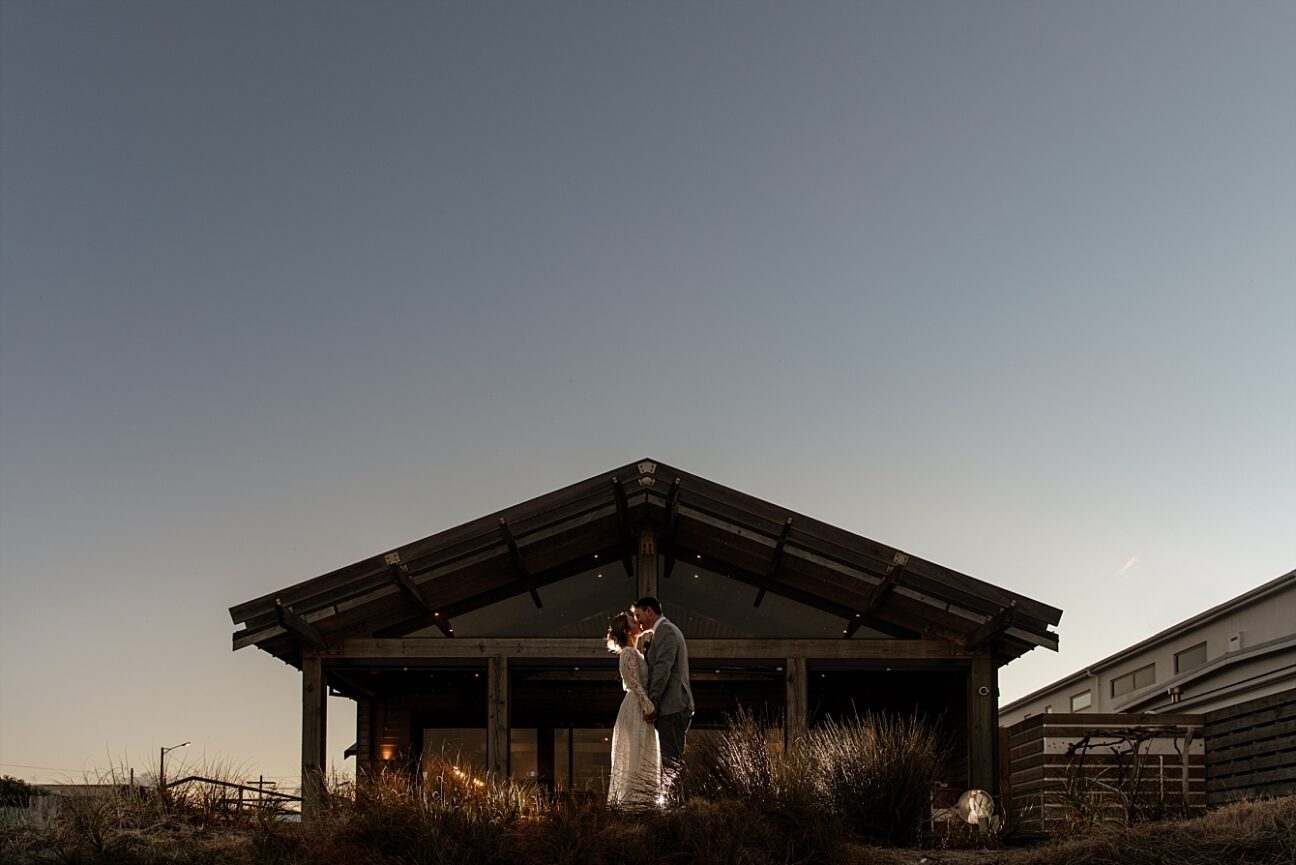 Bride and groom kissing blue light sky