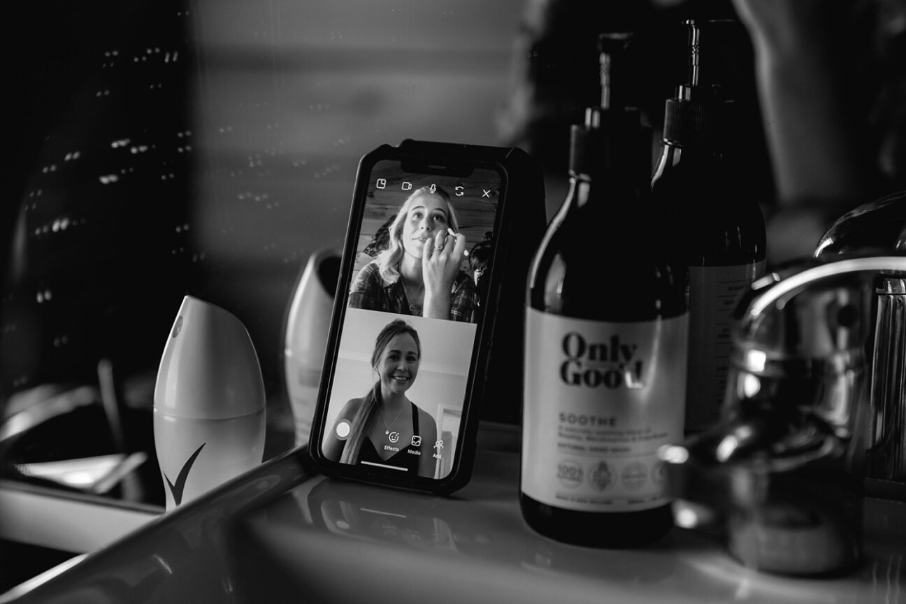 Bride getting ready with sister live streaming on phone