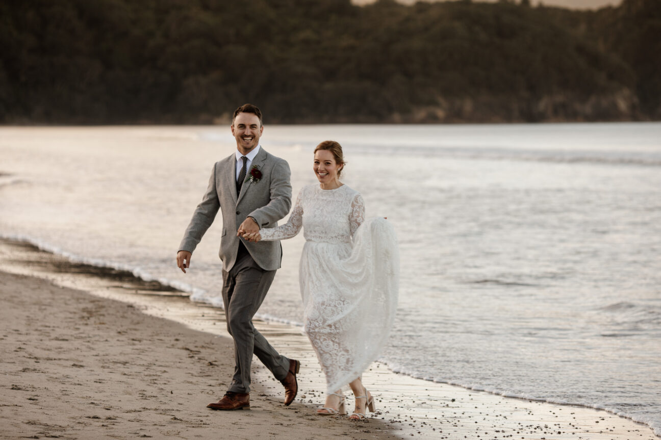 Waihi bride and groom walking on the beach
