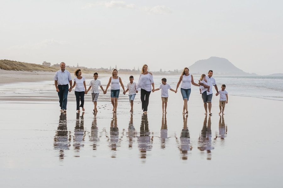 Family walking on the beach with reflection at Mount Maunganui