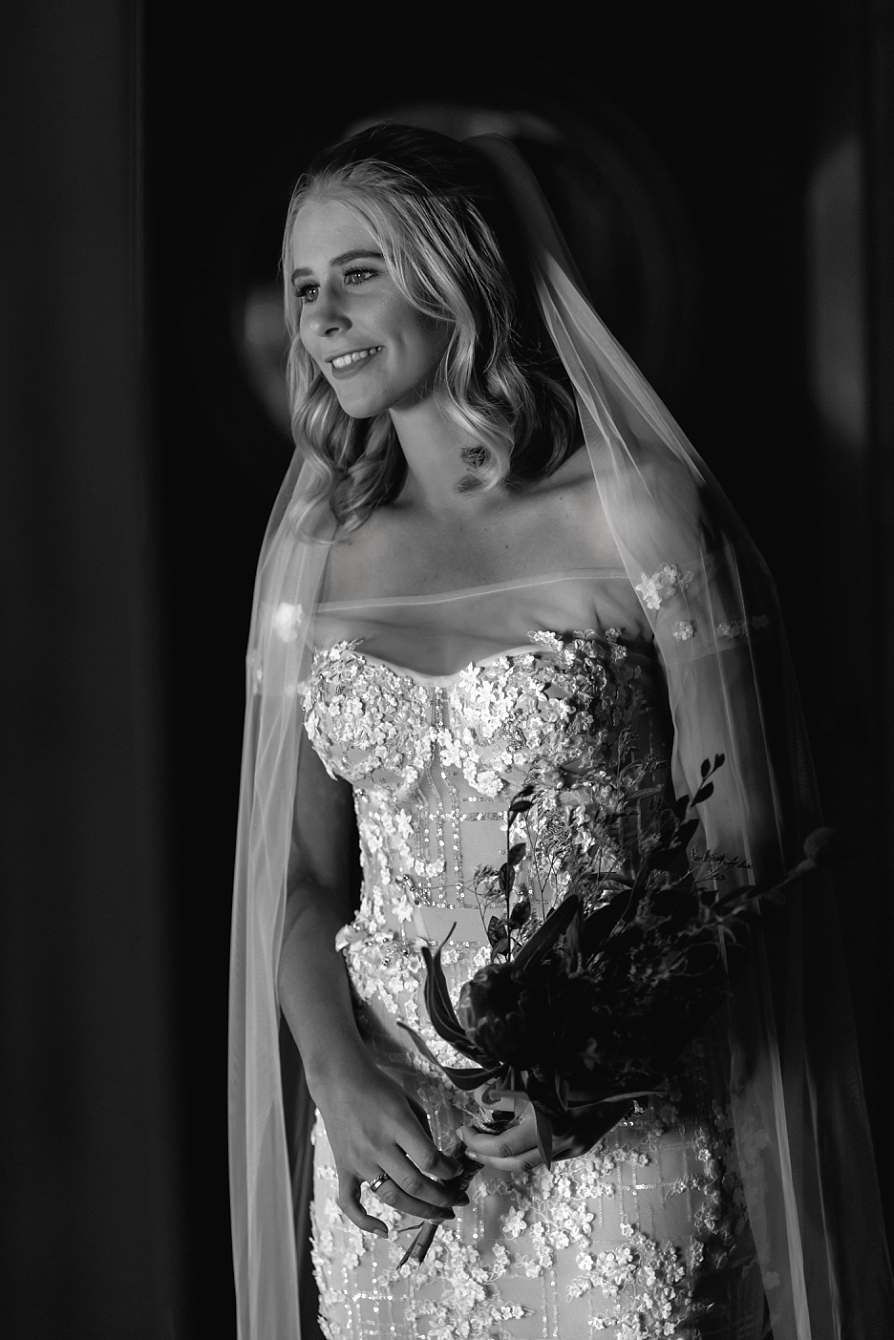 Black and white image of bride in hallway before wedding