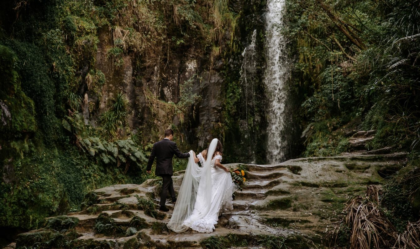 Bride and Groom climbing rocks at Kaiate Falls New Zealand