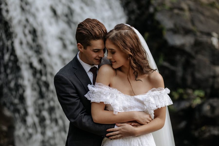 Bride and Groom cuddling in front of waterfall