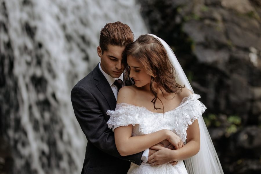 Romantic moment of elopement couple in front of waterfall New Zealand