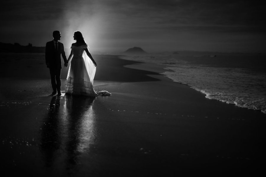 Black and white image of sea spray lit up wedding photo