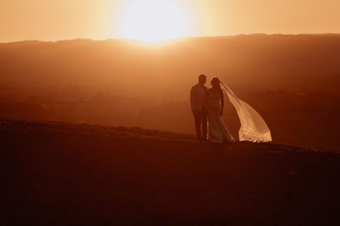 Golden hour sunset photo with bride and groom walking on the hills of Eagle Ridge