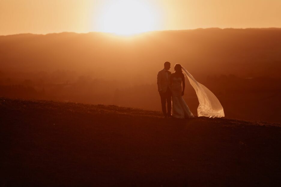 Golden hour sunset photo with bride and groom walking on the hills of Eagle Ridge