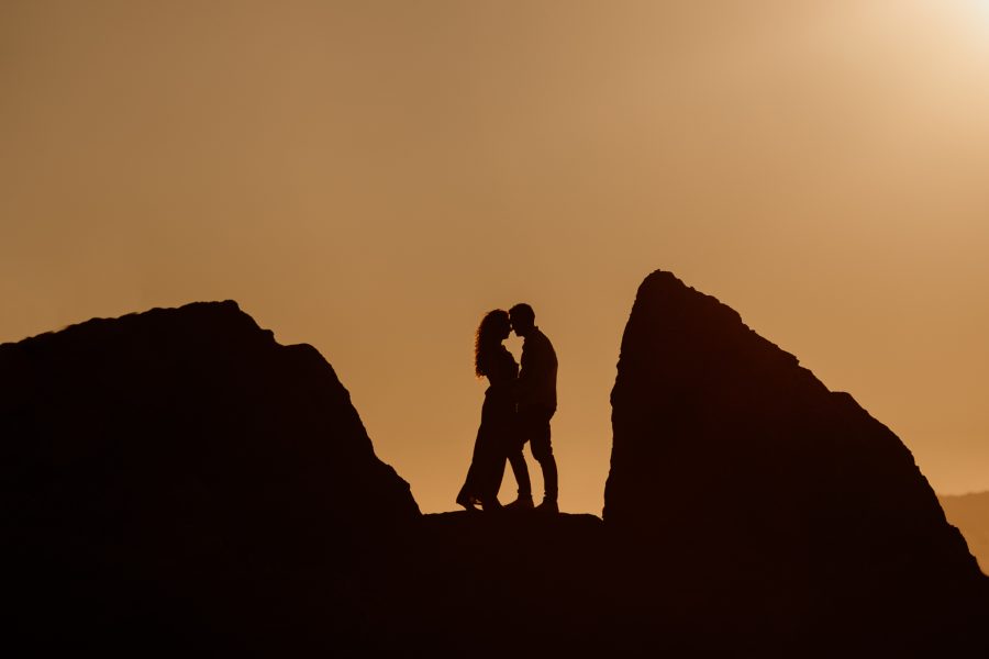 Couple silhouetted on rocks at sunset at Mount Maunganui