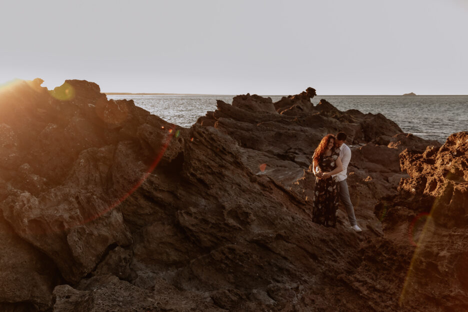Photography on rocks at golden hour with ocean behind them