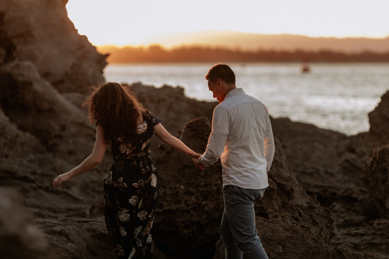 walking over rocks at mount Maunganui at golden hour