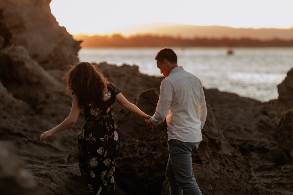 walking over rocks at mount Maunganui at golden hour