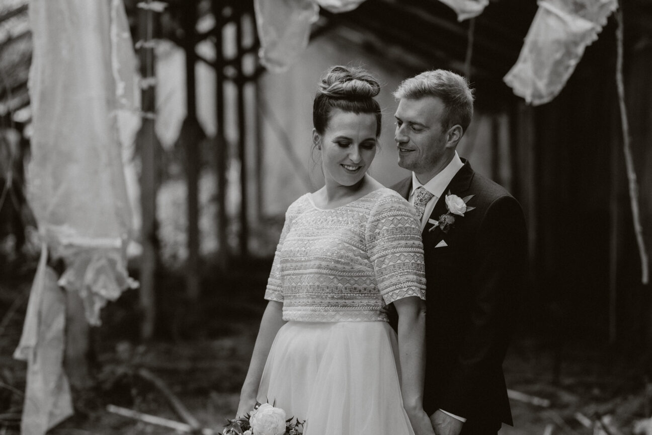 Bridal couple cuddling in old abandoned building moody shot