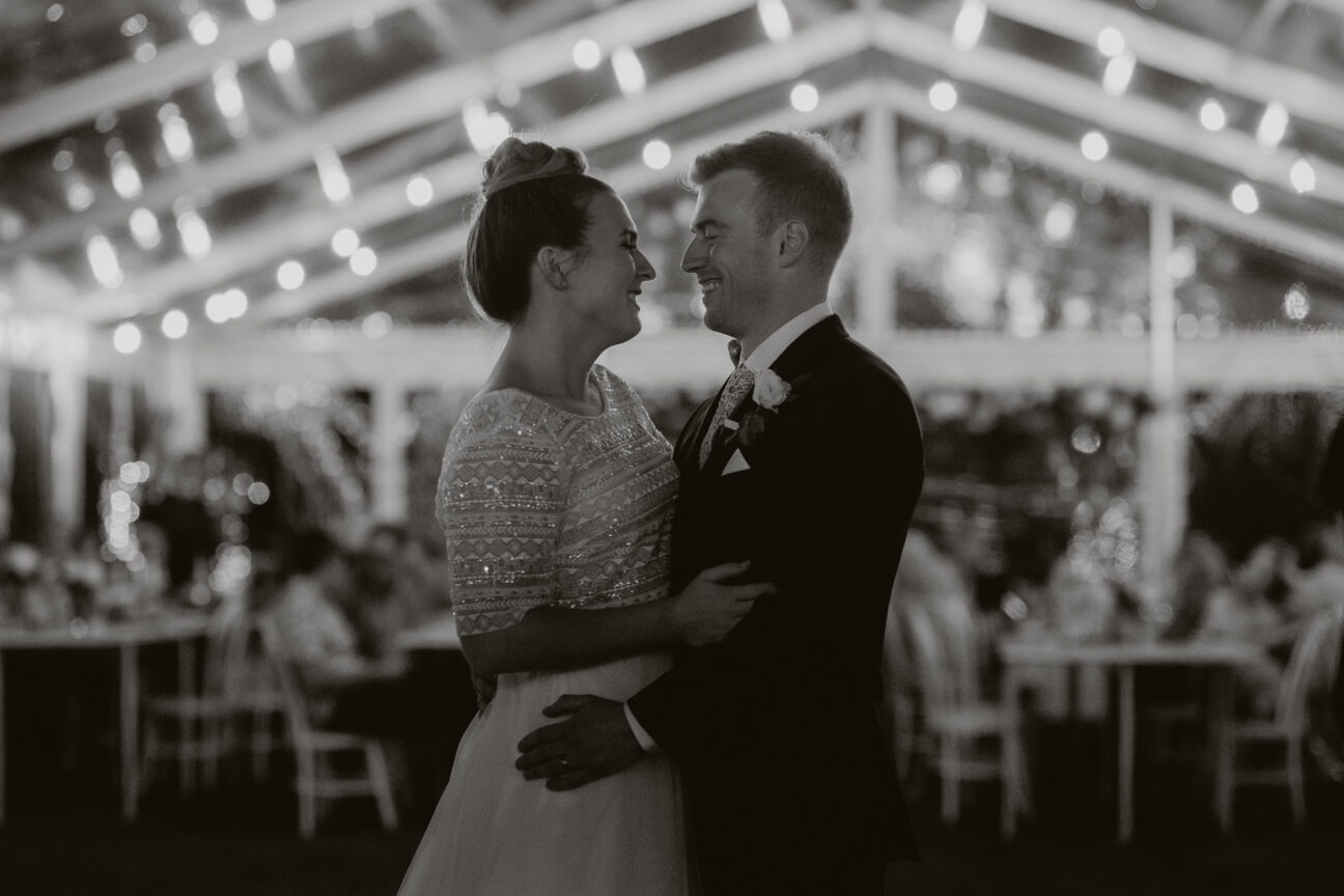 Cuddling happy bride and groom inside wedding marquee