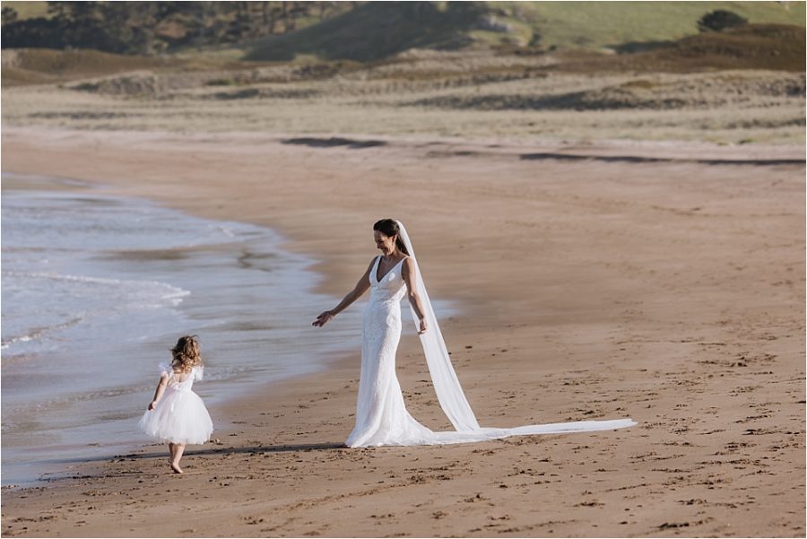 Bride embracing flower girl on Hot Water beach