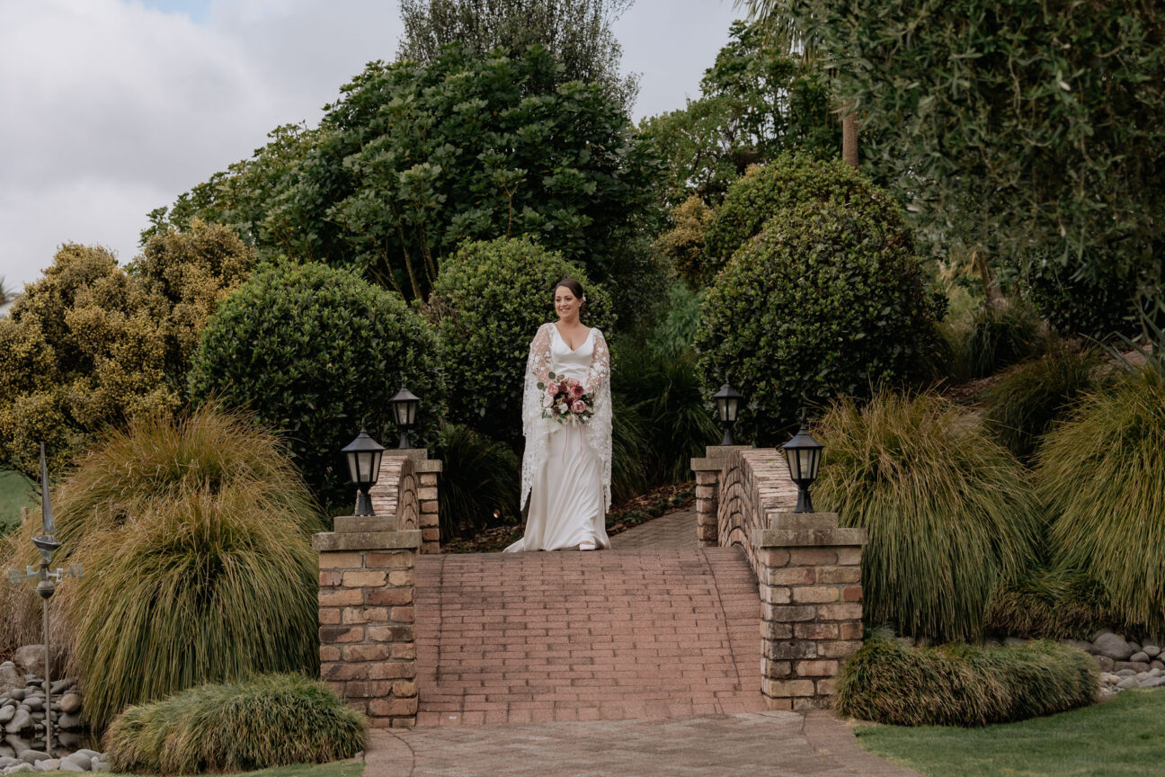 bride walks to groom on brick bridge