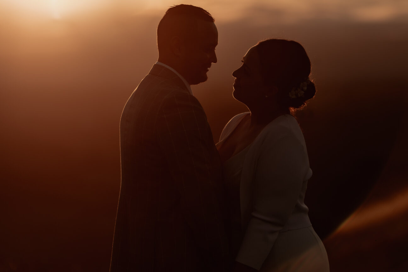 Couple looking at each other in moody wedding image at golden light
