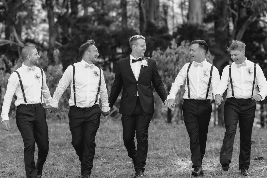 Groomsmen walking holding hands laughter