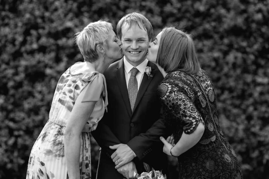 Mother of groom and sister kissing groom