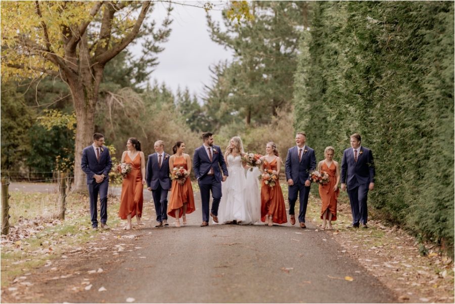 Rust and navy bridal party on driveway laughing walking