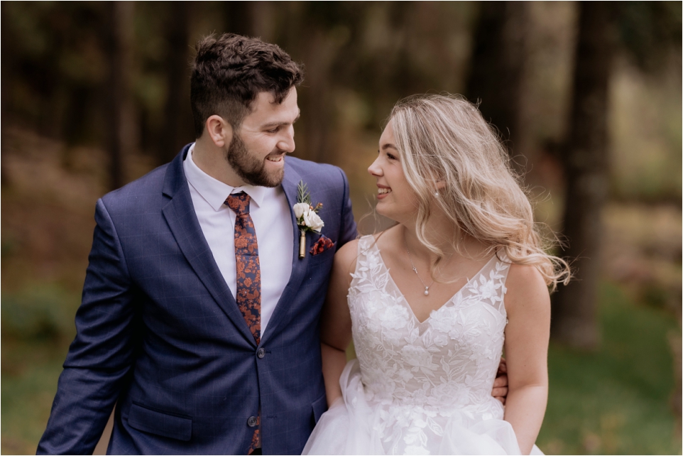 Happy relaxed bride and groom walking in the woods at Makoura Lodge