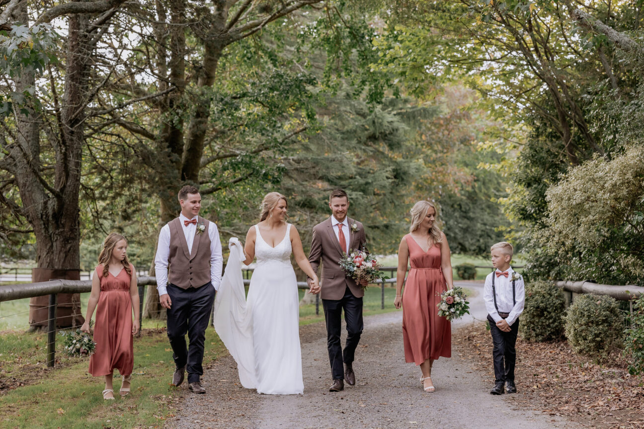 wedding party walking with page boy and flower girl in coral dresses