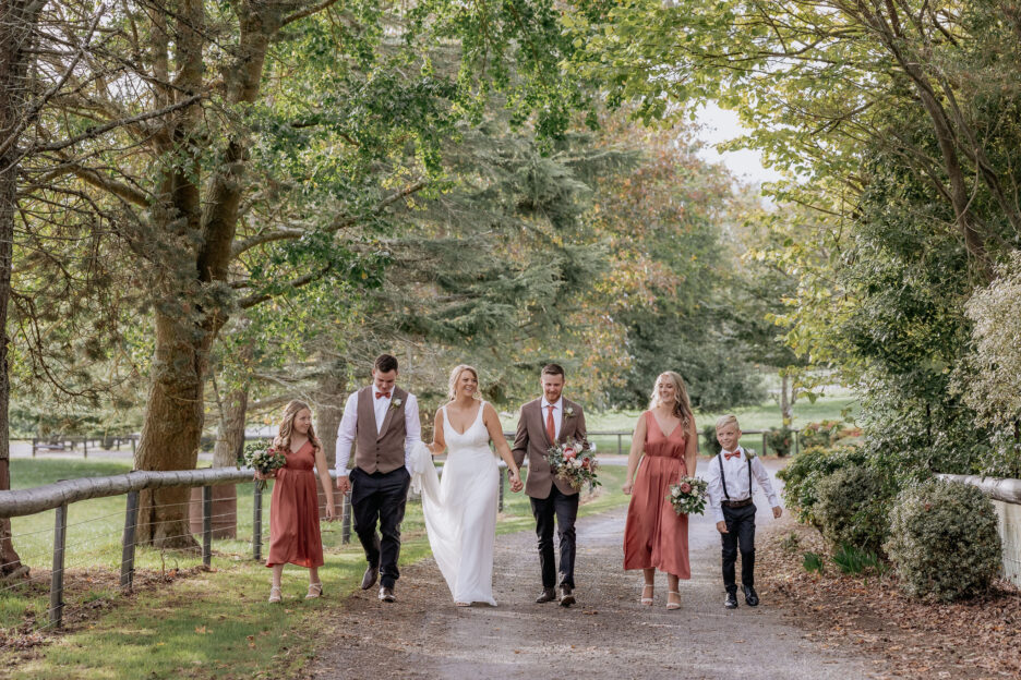 wedding party walking on country driveway in waikato in coral dresses
