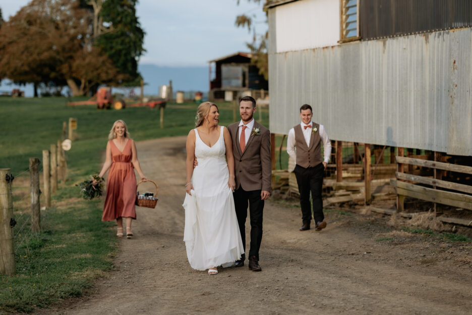 Happy wedding party walking with bridesmaid holding picnic basket