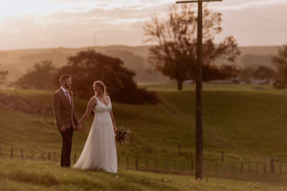 Bride and groom walking over farm at waikato wedding