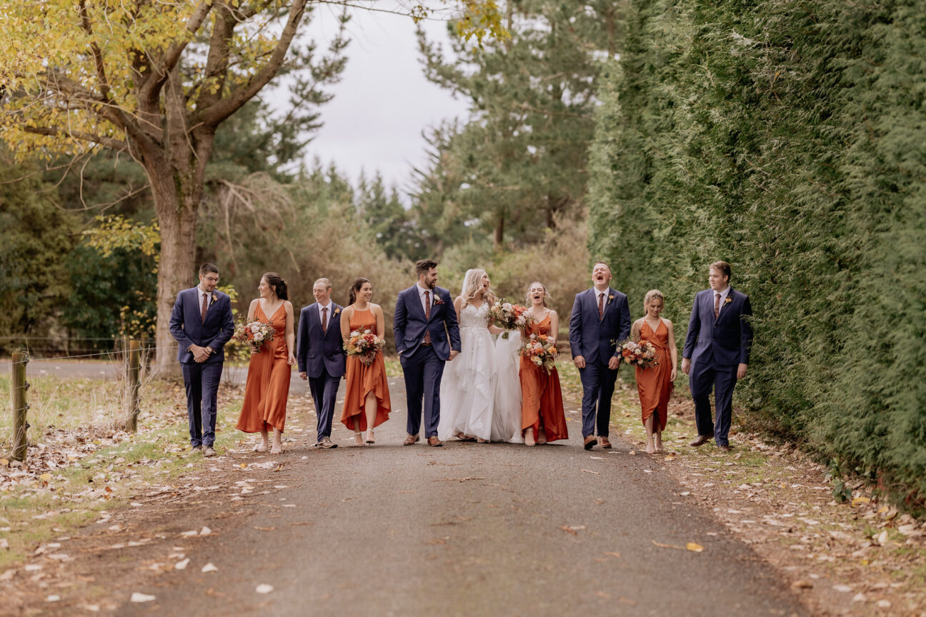 Makoura Lodge orange wedding party walking on driveway laughing