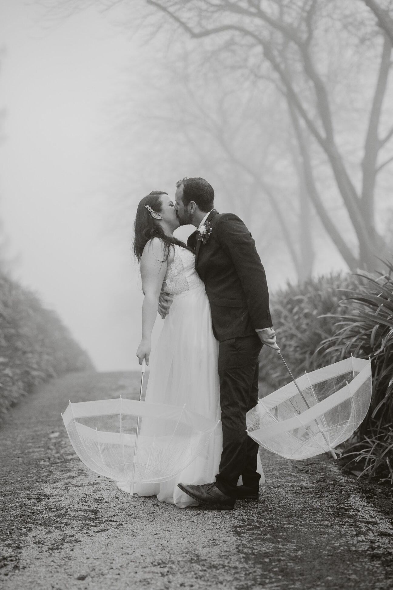 Bride and groom kissing in the rain