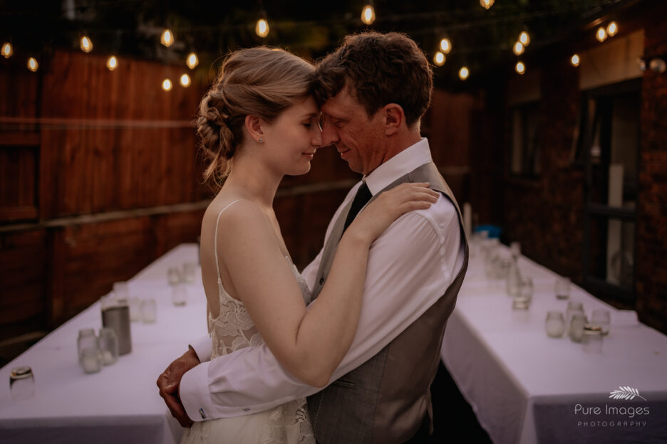 bride and groom under the lights in backyard wedding