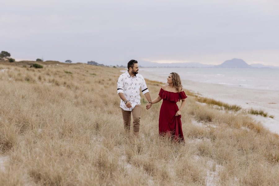 couple walking in red dress photo shoot papamoa dunes