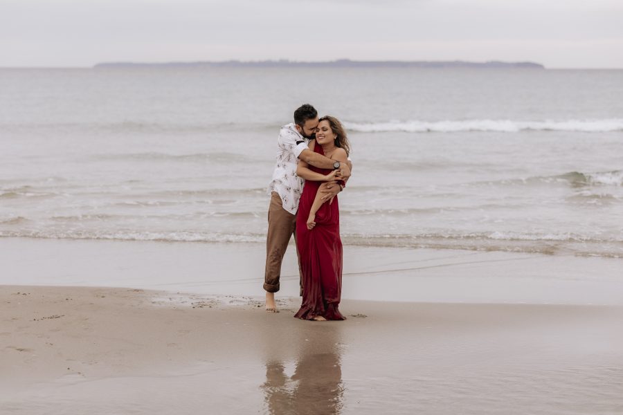 couple hugging on papamoa beach during beach photoshoot