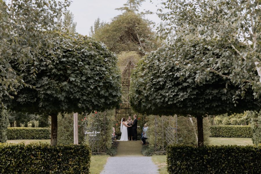 Wedding ceremony in progress peeking into entrance of tree church