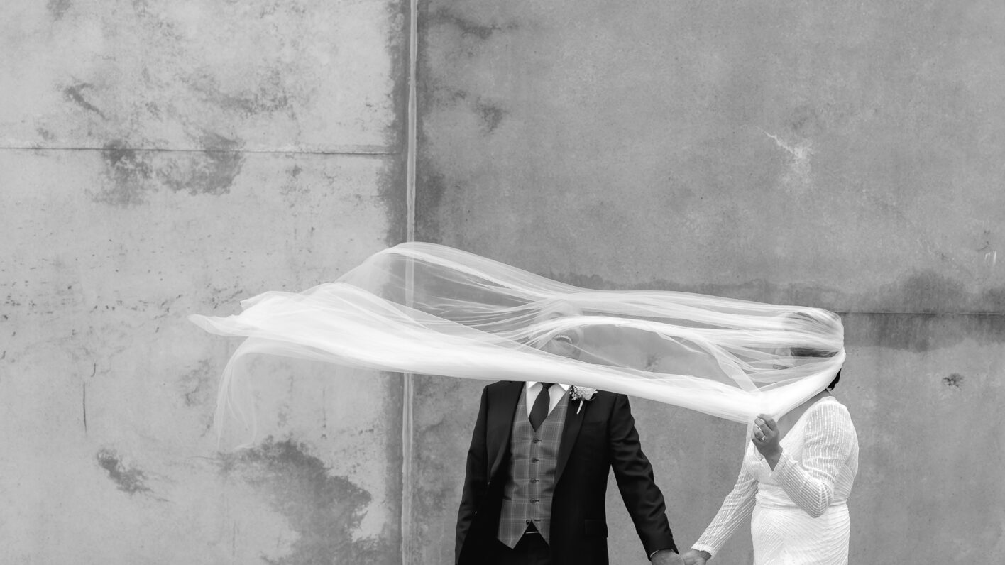 Laughing groom as brides veil flies up