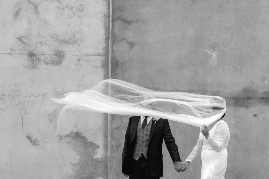 Laughing groom as brides veil flies