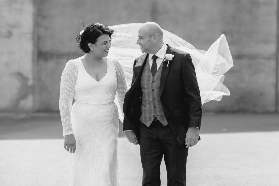 Wedding photos with veil blowing behind couple walking