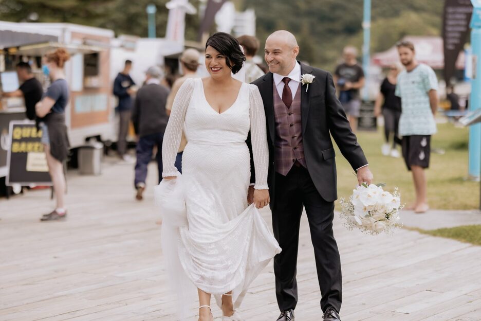 Bride and groom enjoying walking the board walk on Mount Maunganui Beach