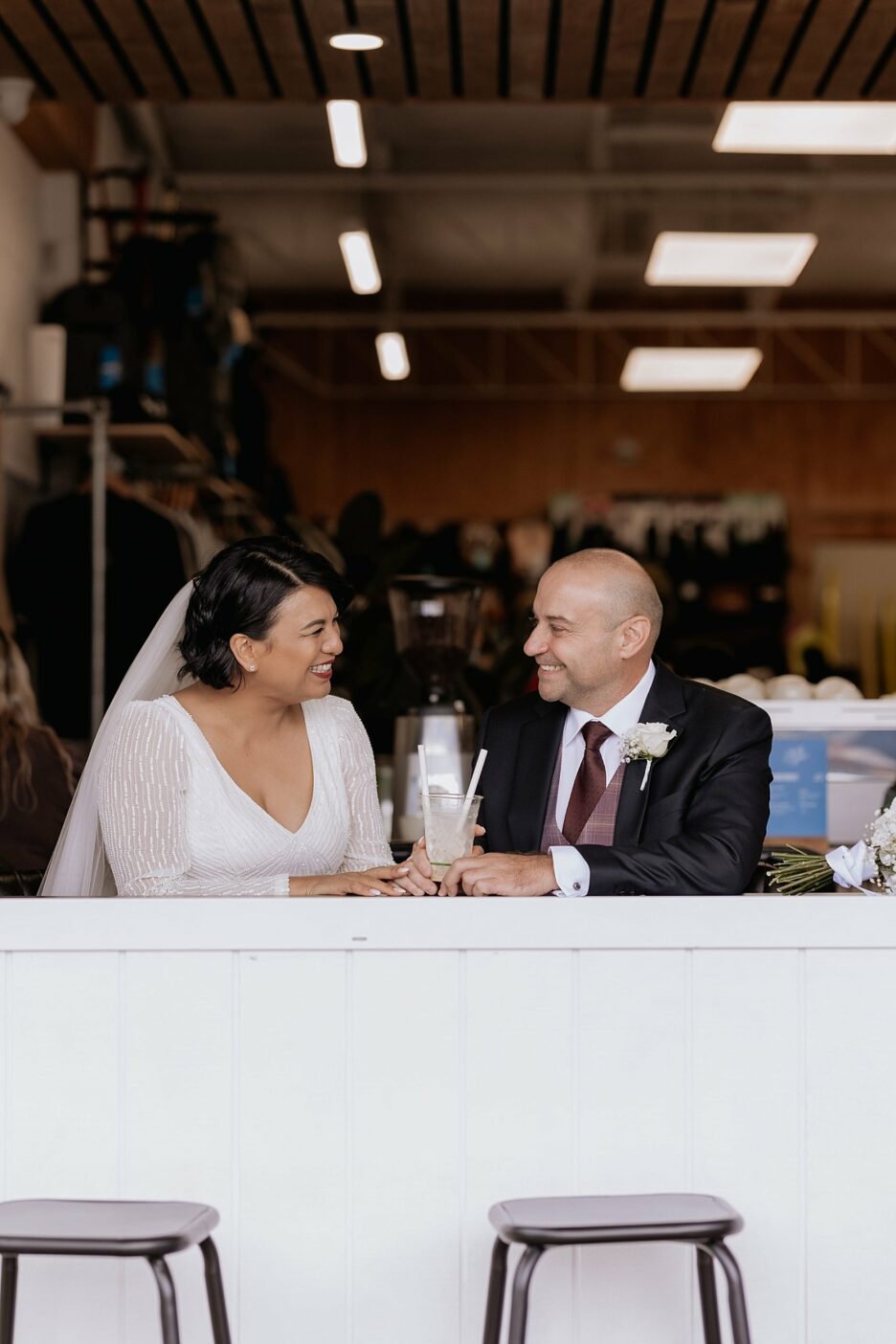 wedding couple enjoying milkshake at cafe window during urban street photography